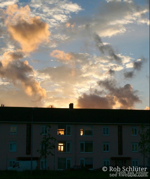 Zonsondergang waarbij de zon ook door een woning heen zichtbaar is.