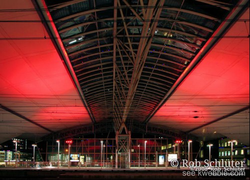 Een verlicht perron overkoepeld door een rood beschenen plafond.
